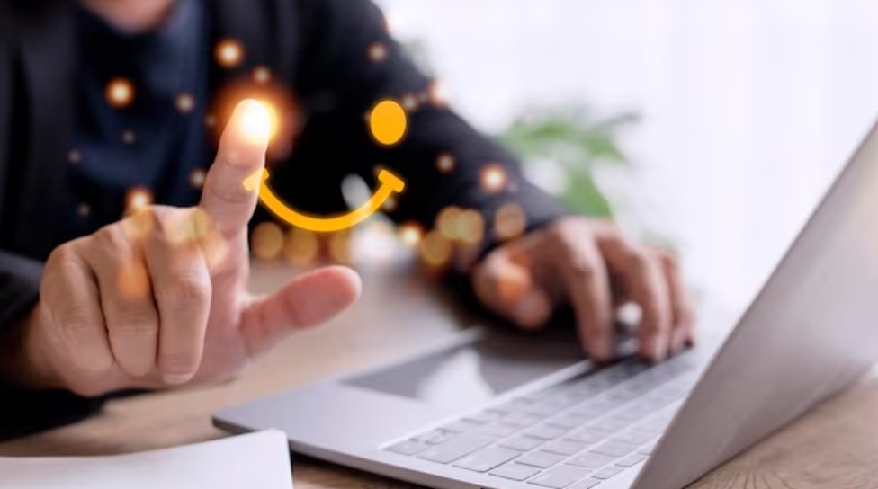 a person using a laptop and drawing a virtual smiley face with the finger